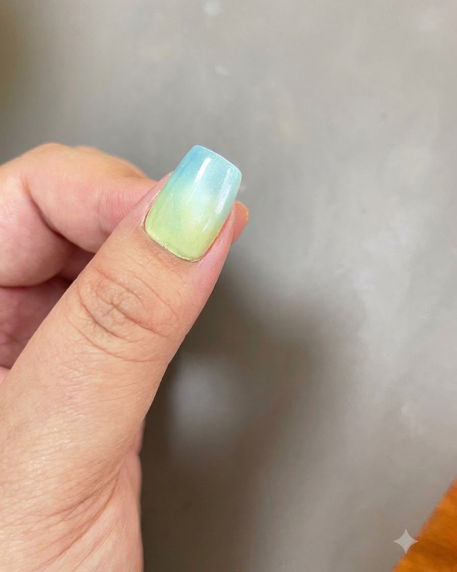 Ein Fingernagel mit blau-gelbem Ombré und kreisförmigem Cat-Eye-Lichteffekt unter einer UV-LED-Lampe.