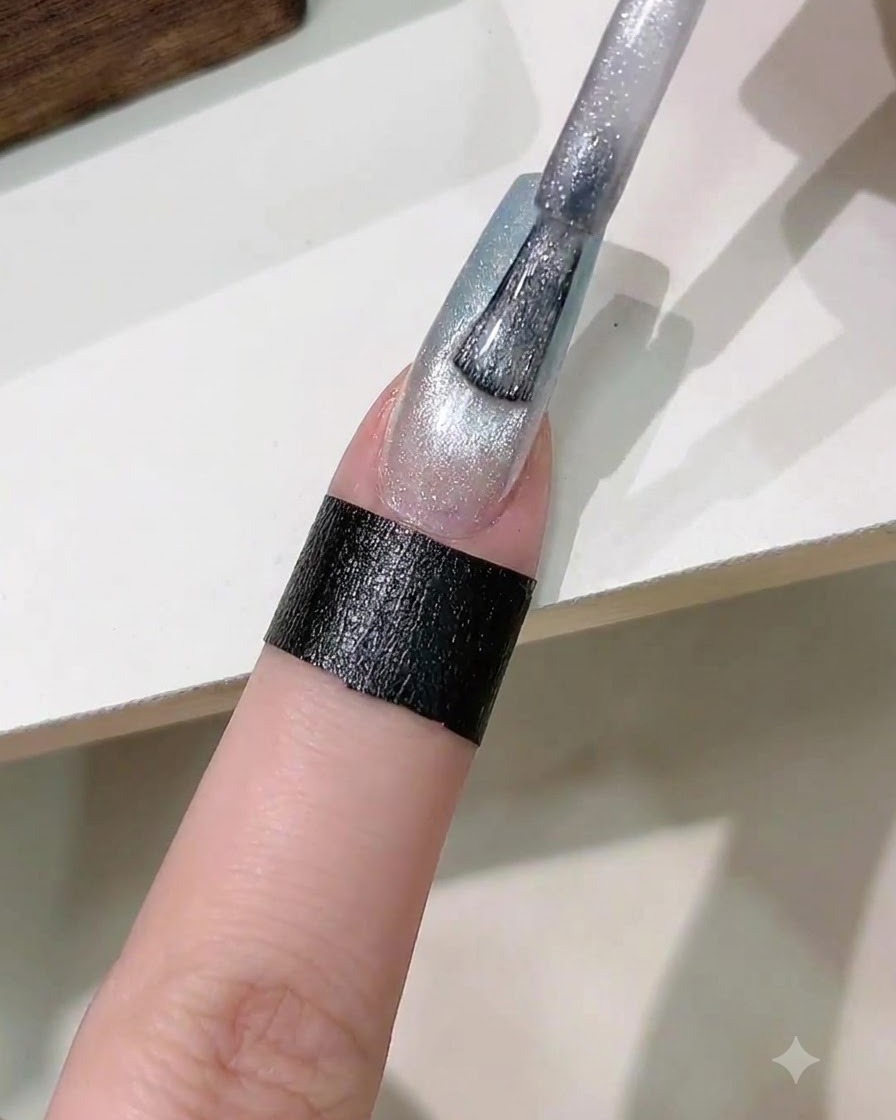 Ein Pinsel trägt eine Schicht silbernes Magnet-Cat-Eye-Gel auf den Farbverlauf-Nagel auf.