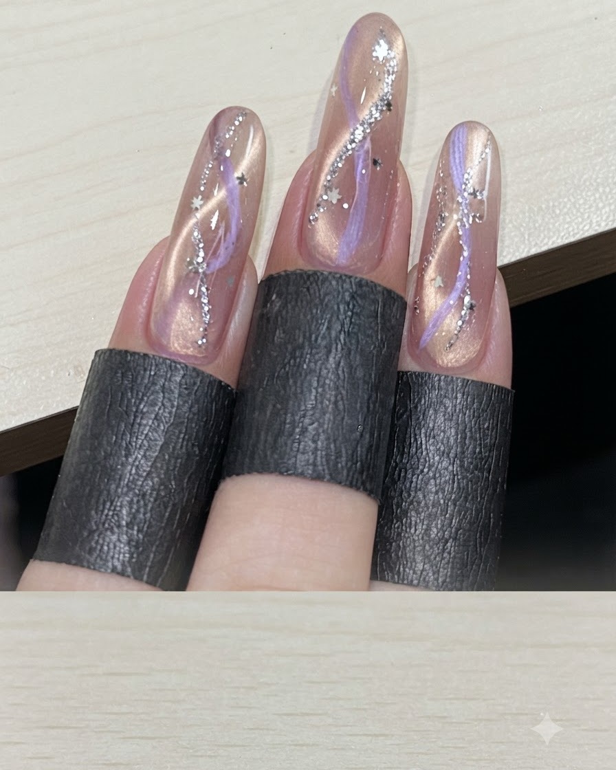 Mehrere Finger zeigen fertiggestellte Ribbon-Cat-Eye-Maniküren mit Sternen-Pailletten.