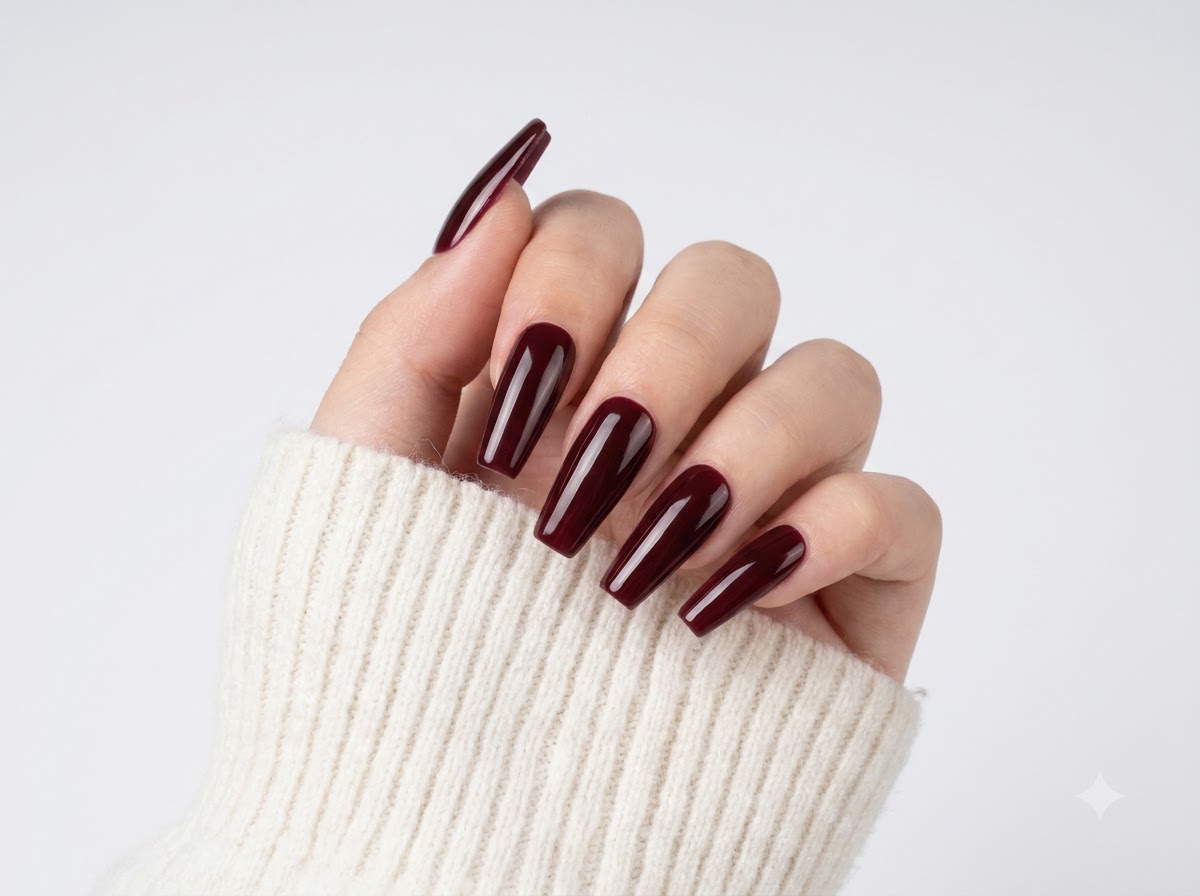 Ausgestreckte Finger zeigen transparente Nude-Basen und tief weinrote Spitzen mit einem glänzenden Finish.