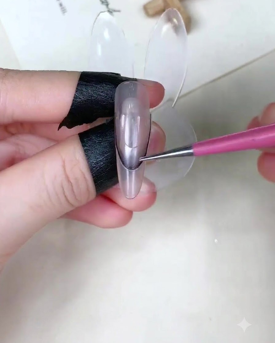 Nahaufnahme eines Fingers, der eine geschwungene French-Schablone auf einem transparenten Nagel-Display hält.