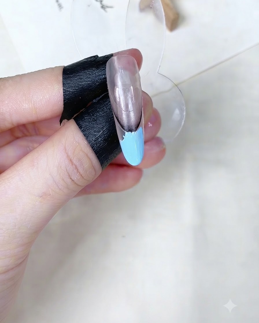 Ein Make-up-Schwämmchen tupft auf den babyblauen Gelbereich auf einem Nagel-Display.