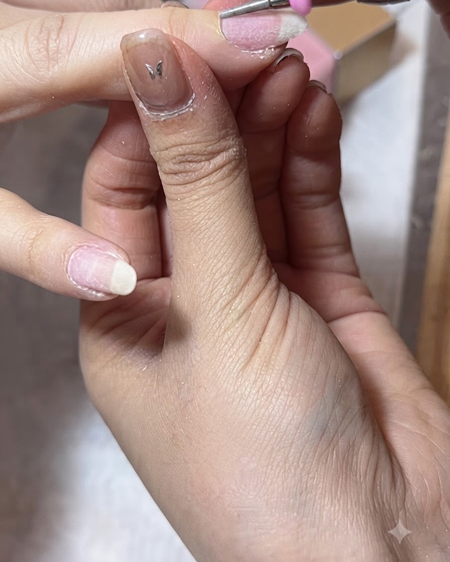 Ein Fräser reinigt die seitlichen Nagelfalze an einem Daumen während der Nagelhautvorbereitung.