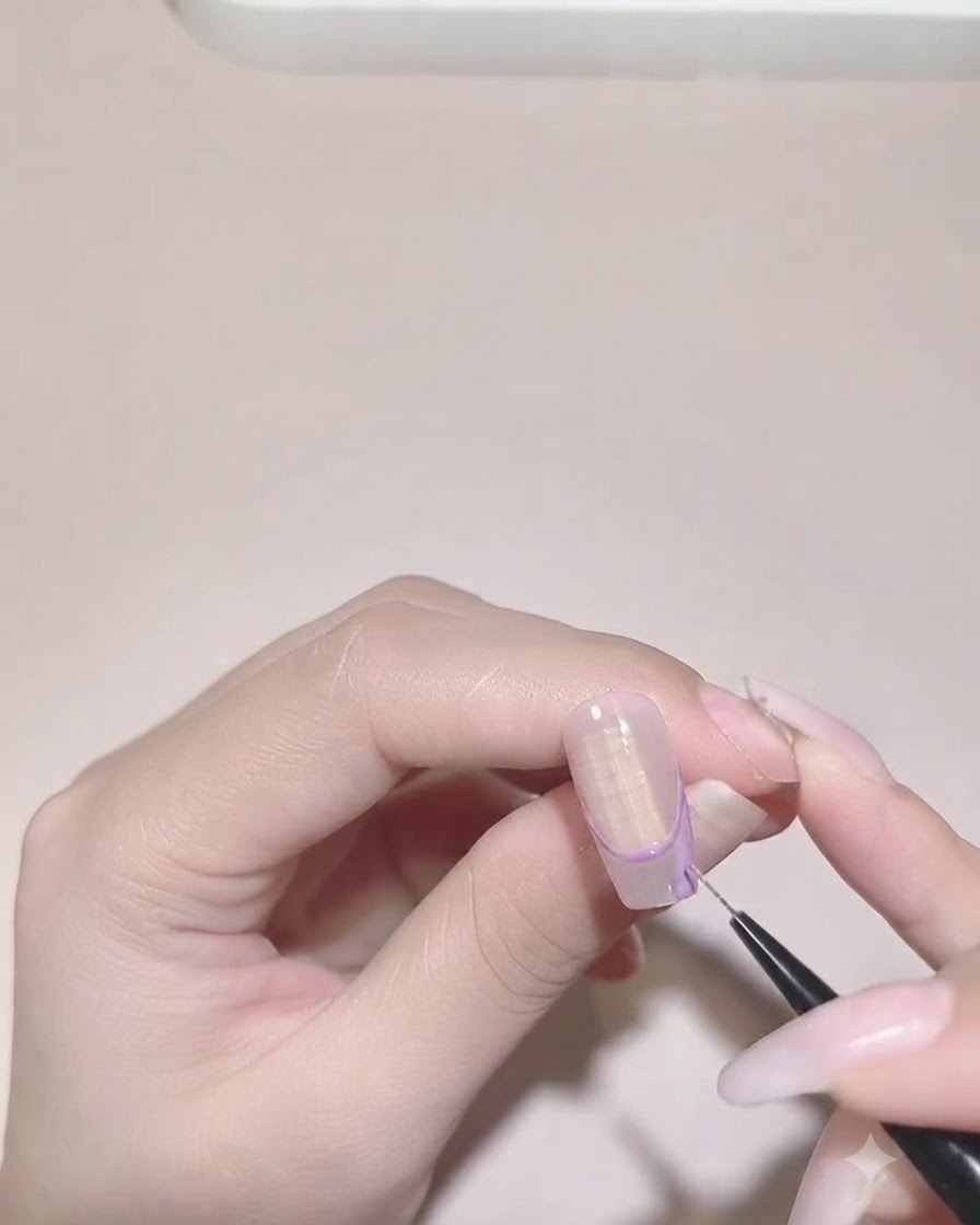 Ein Detailpinsel füllt die lila Farbe innerhalb der unregelmäßigen French-Tip-Begrenzung auf einem Nagel aus.