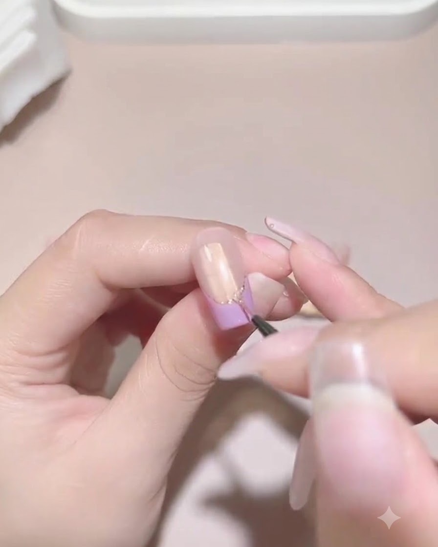 Ein feiner Detailpinsel trägt sorgfältig Versiegelungsgel um die Basis von befestigten Perlen und Strasssteinen auf einem manikürten Nagel auf.