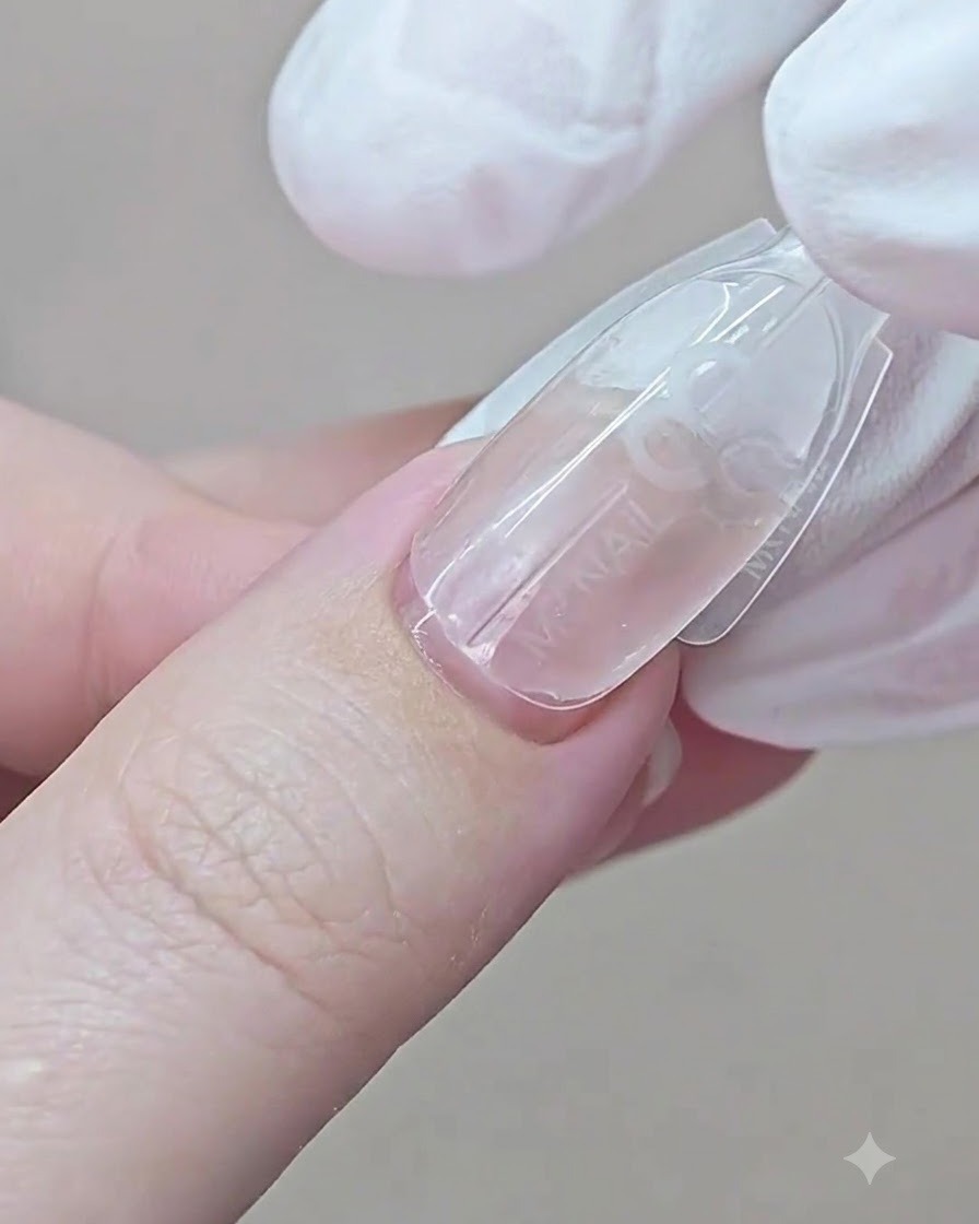 Eine be Handschuh bedeckte Hand drückt eine Dual Form auf einen Fingernagel, beginnend am Nagelhautbereich.