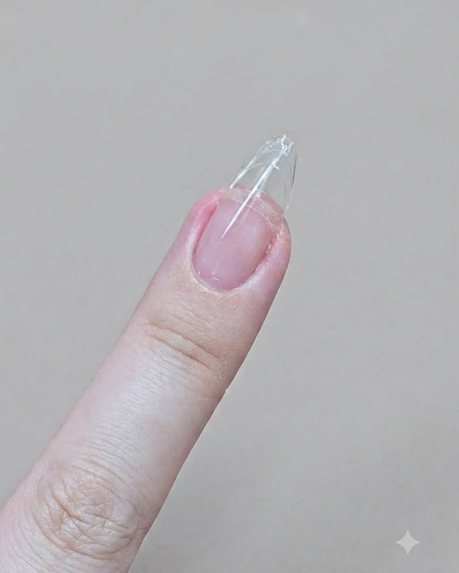 Ein Finger mit transparenter Gel-Extension wird mit einer Sandblattfeile in eine scharfe Mandelform gefeilt.