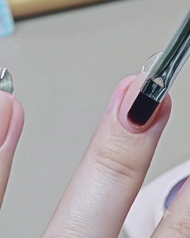 Ein Nail-Art-Pinsel trägt einen glänzenden, klaren Top Coat auf einen fertigen French-Maniküre-Nagel auf.