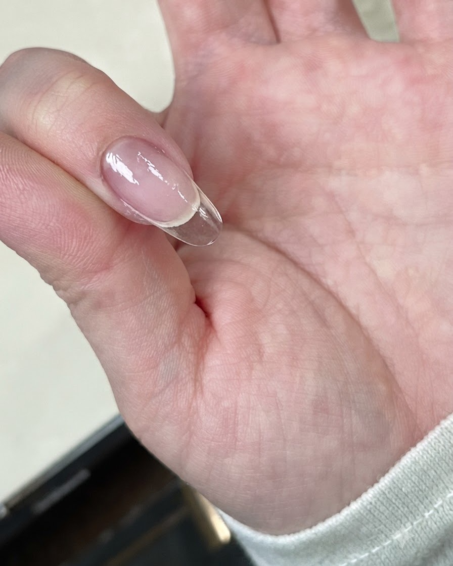 Eine Hand, die eine Nagelspitze unter eine Mini-LED-Lampe hält.