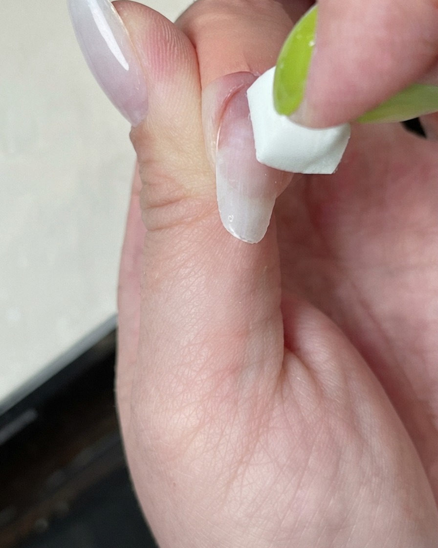 Ein Nagel, der unter einer Mini-Härtungslampe mit weißem Lichtschein ausgehärtet wird.