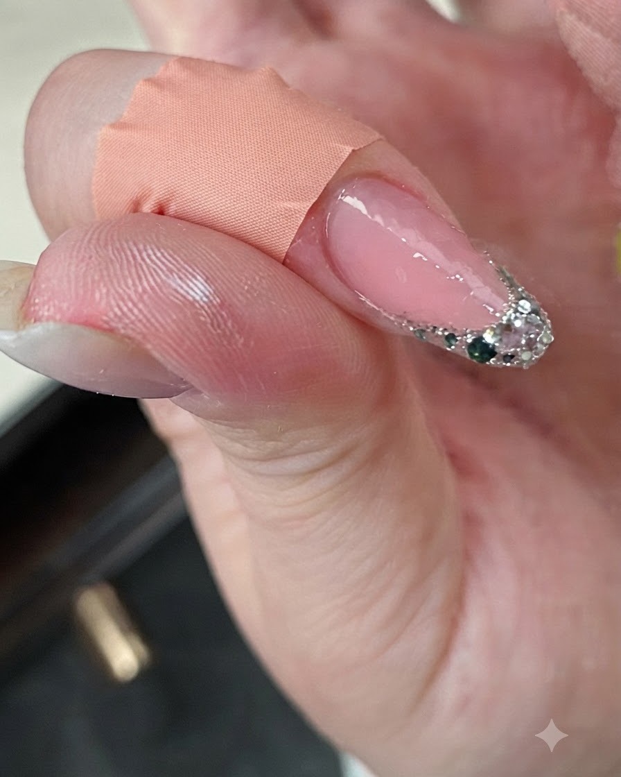 Ein Finger mit einer Glitter-French-Spitze während des Aushärtens in der Nähe einer Mini-UV-Lampe.