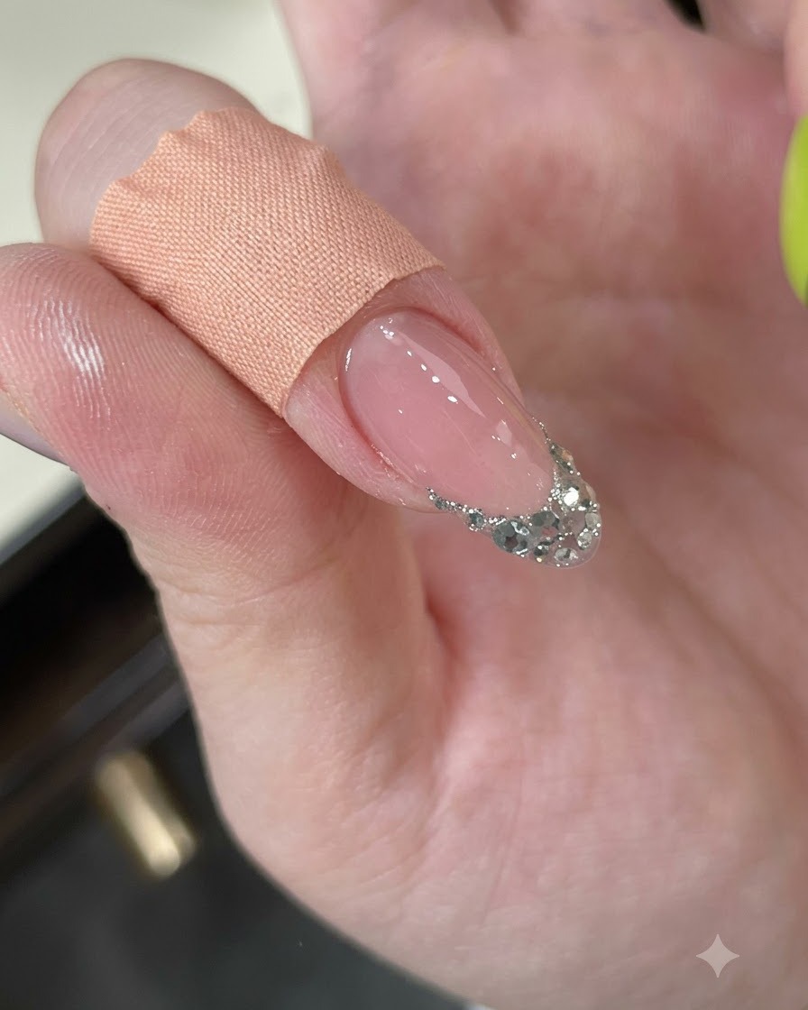 Ein Finger, der mit einem Reinigungspad abgewischt wird und eine strukturierte Silberglitter-French-Spitze zeigt.