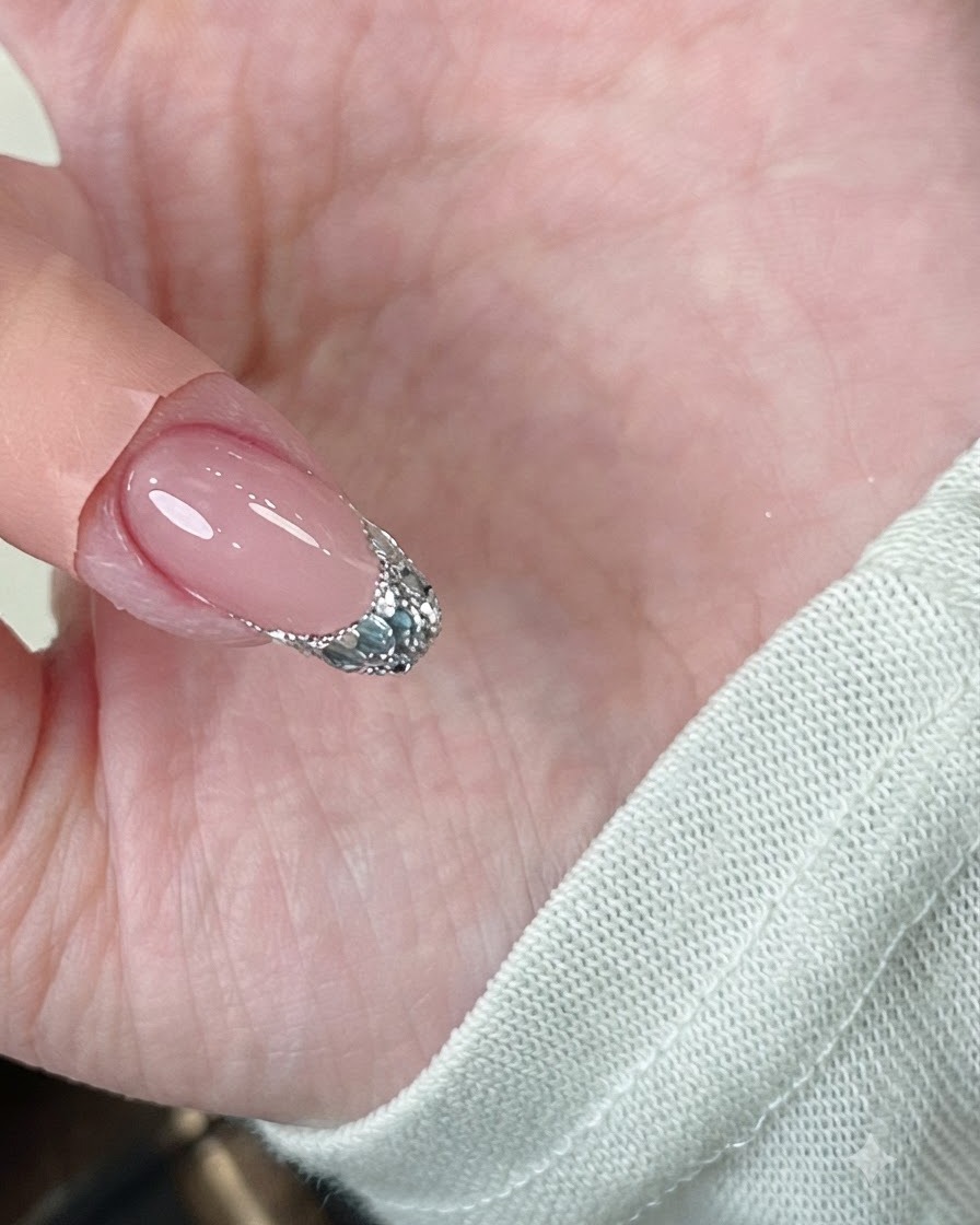 Eine Pinzette, die während des Aushärtens unter einer Lampe sanft die Seitenwände eines gellackierten Nagels zusammendrückt.