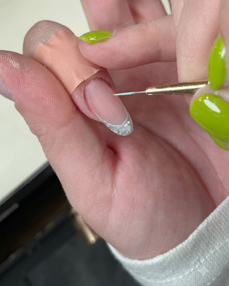 Ein Fingernagel mit einer zarten blauen Randlinie unter einer Mini-LED-Härtungslampe.