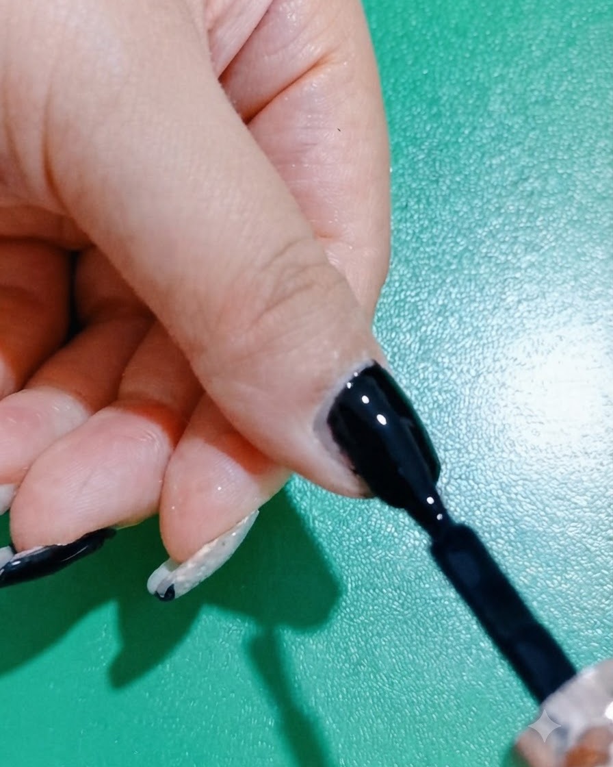 Ein Nagelpinsel glättet und verfeinert eine Schicht schwarzen Gel-Lacks auf einem Fingernagel.