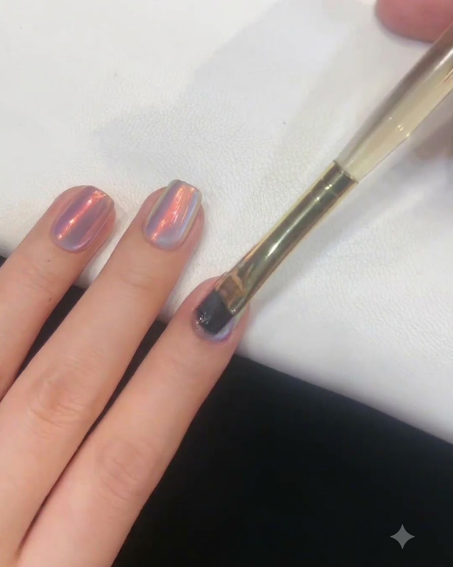 Ein Nagelpinsel, der sanft eine dünne Gelschicht auf einen mit Aurora veredelten Fingernagel aufträgt.