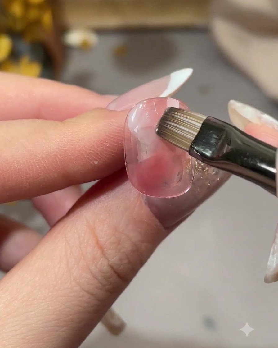 Ein Pinsel verblendet die Kanten des weißen Gels in den Nageluntergrund.