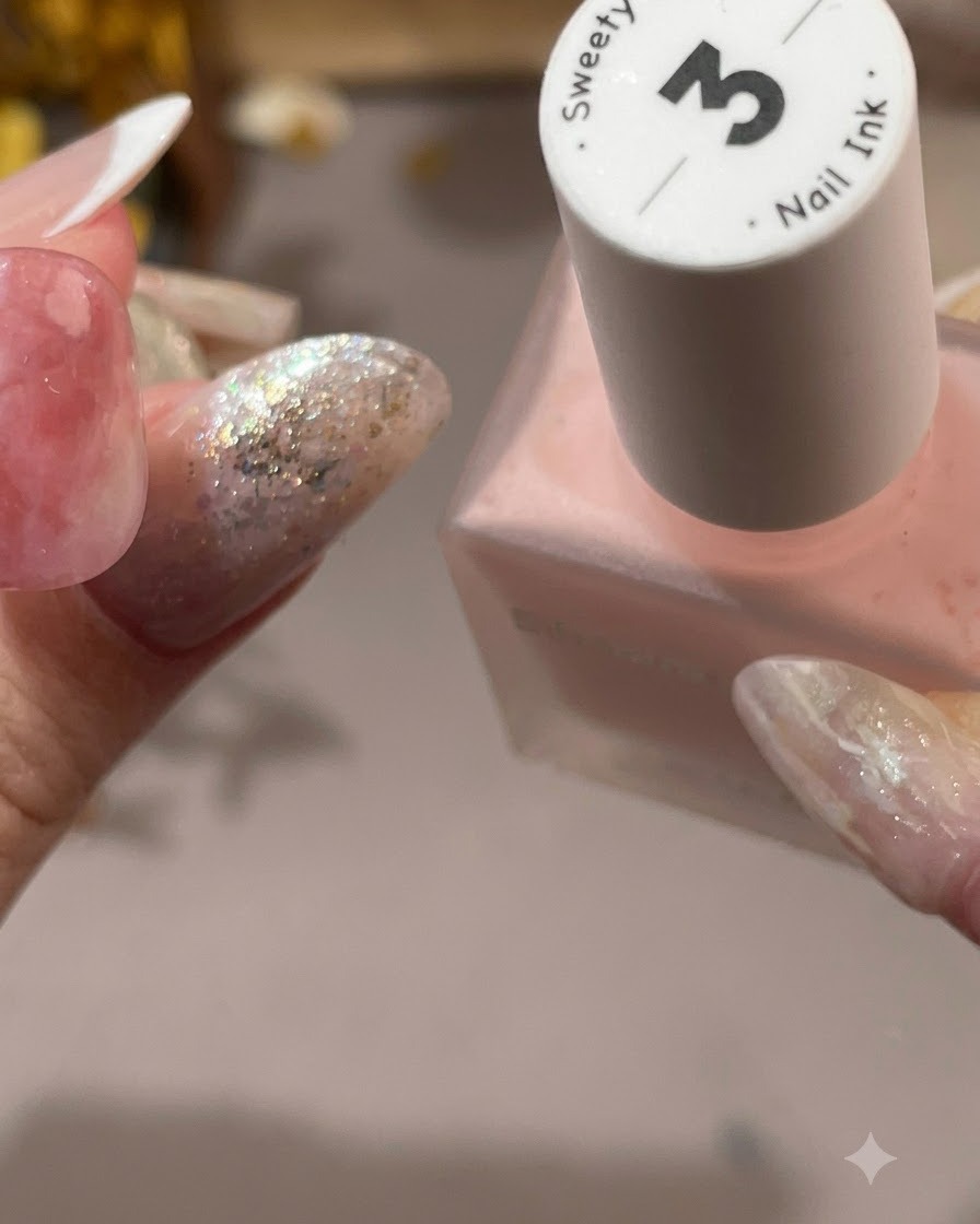 Eine Flasche sanftes rosa Blooming Liquid neben einem verzierten Nagel.
