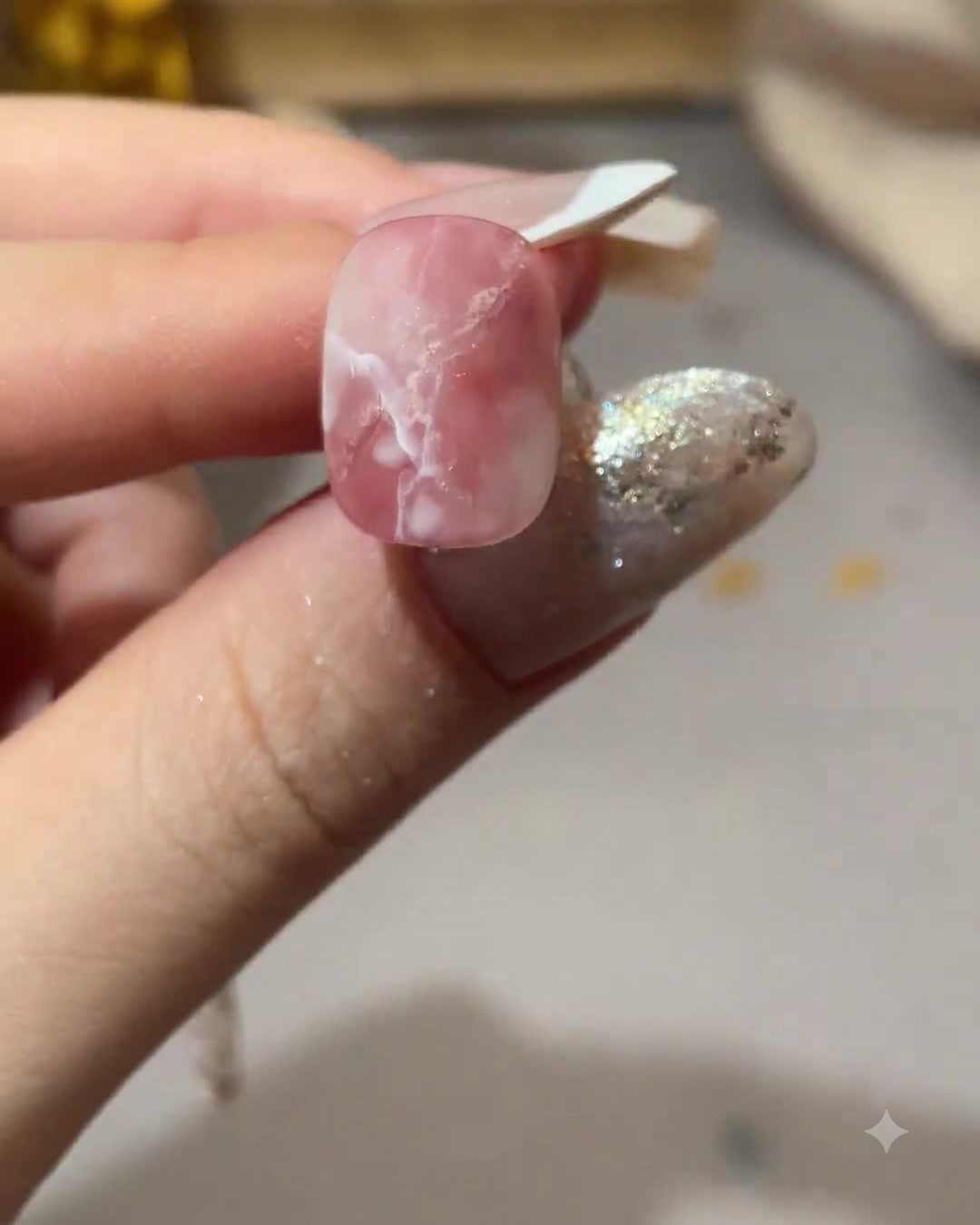 Eine Nahaufnahme eines rosa-weiß marmorierten Nagels mit hinzugefügten Akzenten von rotem Aquarell-Blooming.