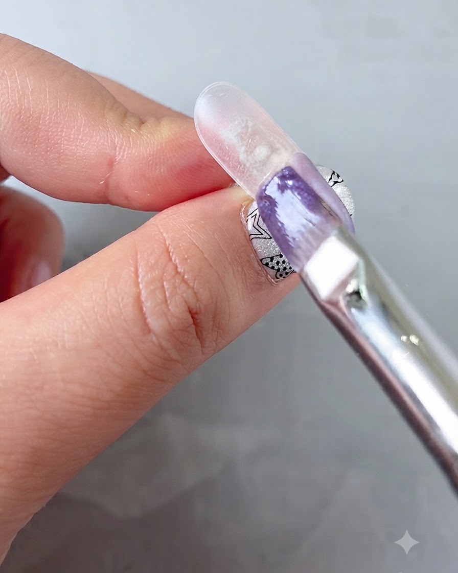 Ein Nagelpinsel, der lila Gel auf einer künstlichen Nagelspitze nach unten verblendet.