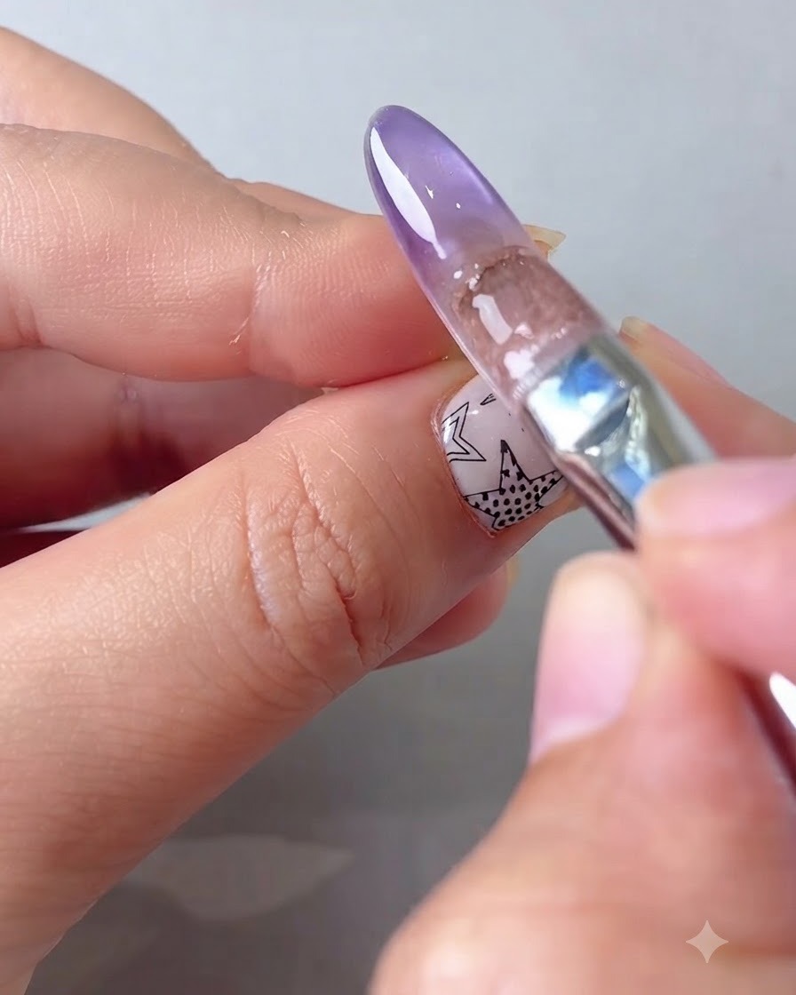 Ein Pinsel, der wasserhelles Sheer-Gel auf die hintere Nagelkante aufträgt.