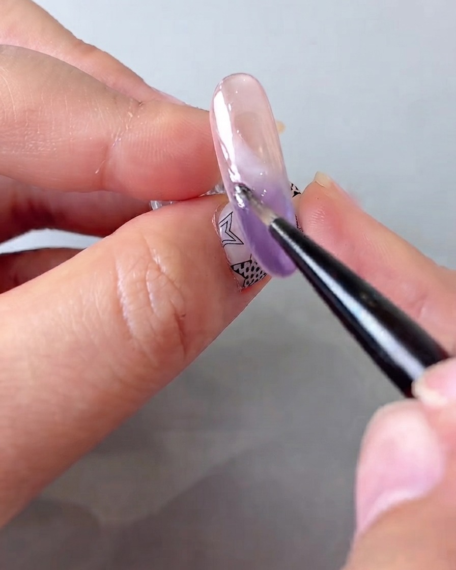 Ein feiner Nail-Art-Pinsel, der einen zweiten präzisen Strich weißes Gel über das bestehende Wolkenmuster aufträgt.