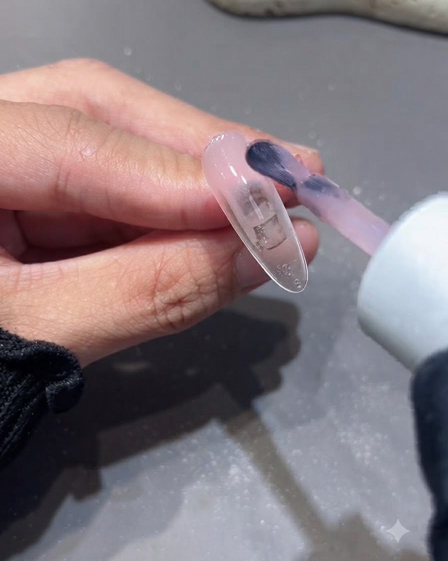 Ein Pinsel trägt die zweite Schicht Nude-Pink-Basisgel auf eine Nagelverlängerung auf.