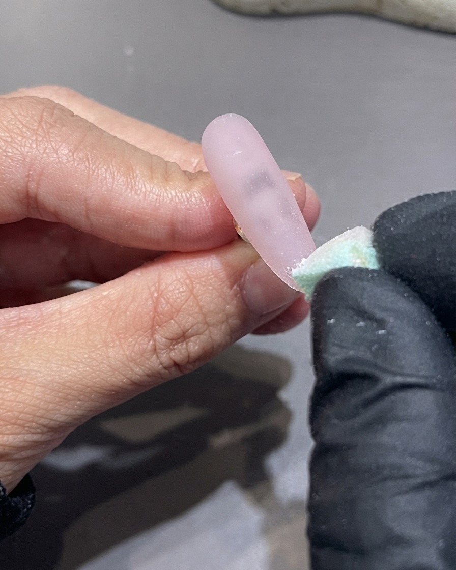 Ein Schwamm tippt senkrecht nach oben von der Nagelspitze, um weißes Gel zu verblenden.