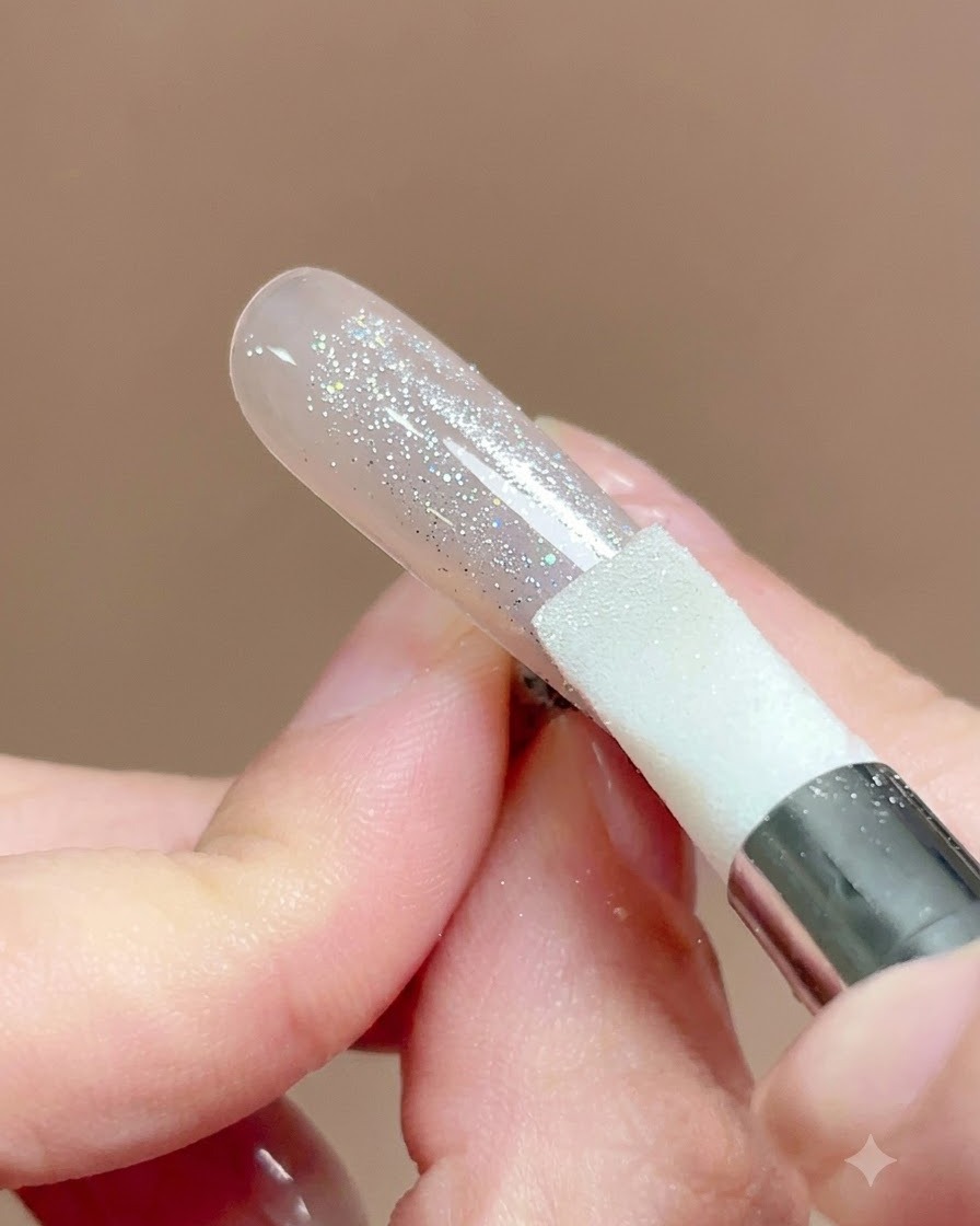 Ein Silikonstift-Werkzeug wird über eine mit Chrompulver bedeckte Nageloberfläche gedrückt und gerieben.