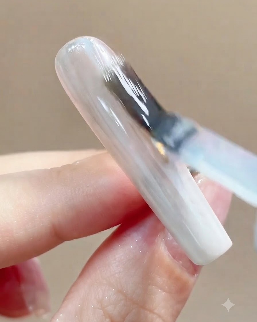 Nahaufnahme eines Nagels, der nach dem Auftragen des Top Coats unter eine UV- oder LED-Aushärtungslampe gelegt wird.