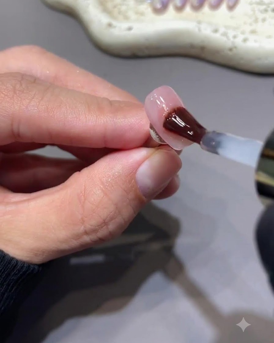 Ein Pinsel trägt einen glänzenden, nicht klebenden Gel-Top-Coat auf einen Nagel mit berryrosa Stern-Nail-Art auf.