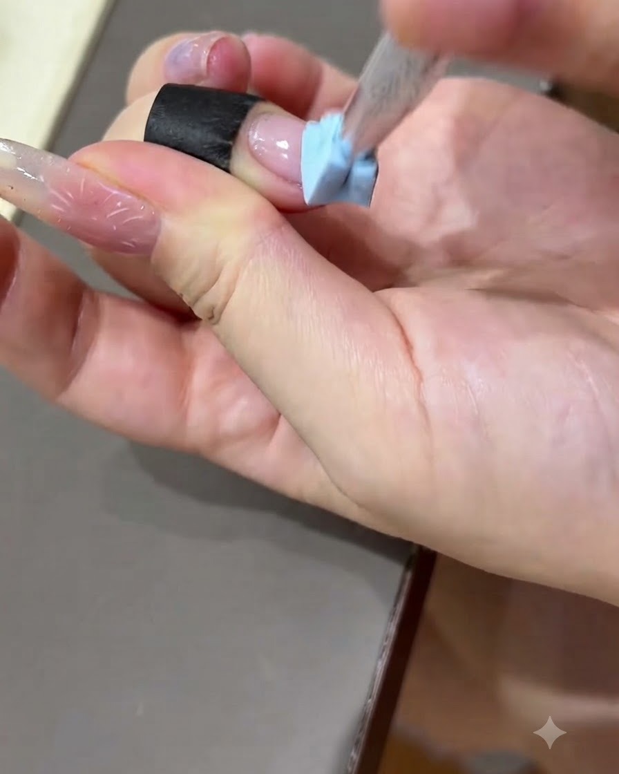 Eine Hand drückt einen schwarzen Übungsstreifen auf die Oberfläche einer Übungsnagelplatte.