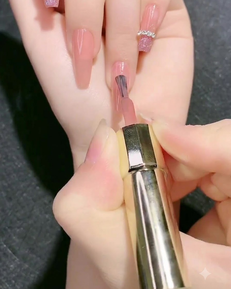 Ein Pinsel trägt eine zweite Schicht Nude-Rosa Base-Gel auf den Fingernagel auf.