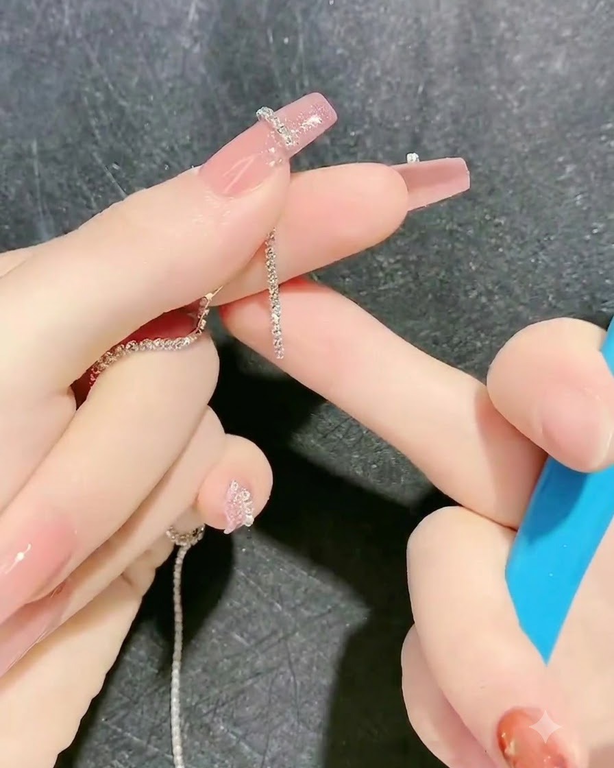 Ein Werkzeug platziert einen Strassketten-Streifen auf den klebrigen Gel-Umriss eines Fingers.