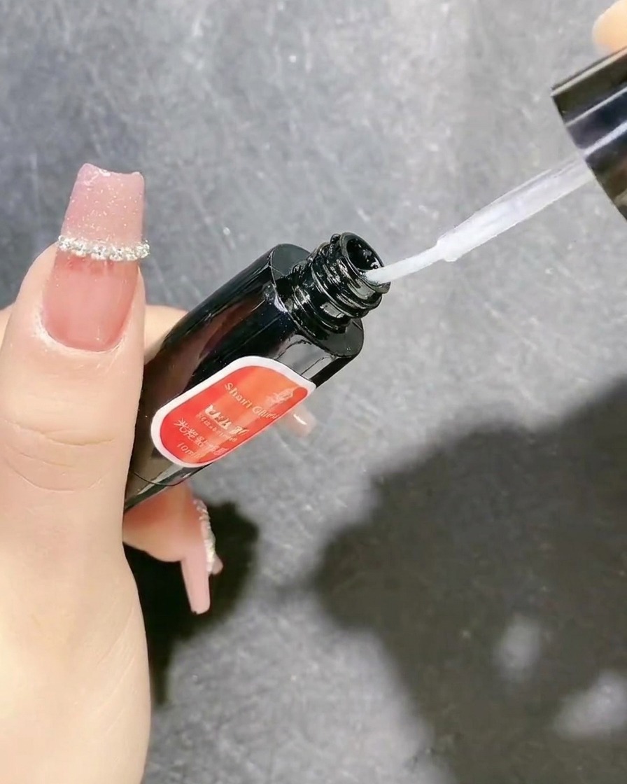 Eine Flasche klaren Versiegelungsgels mit Pinselapplikator wird zum Sichern von Nageldekorationen verwendet.