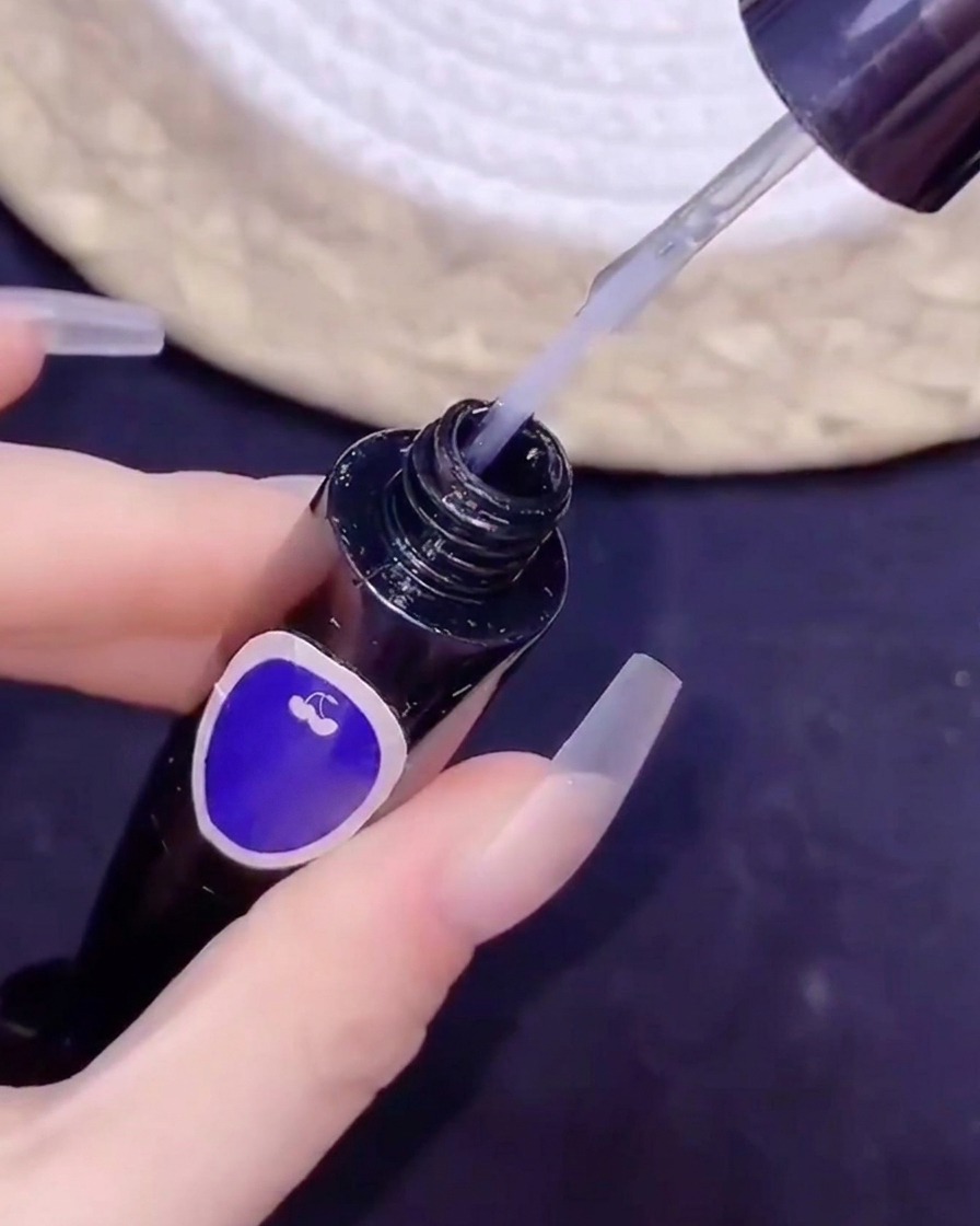Ein feiner Pinsel taucht in eine Flasche No-Wipe-Top-Coat während einer Nail-Art-Anwendung ein.