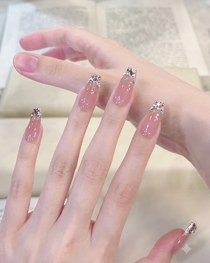 Makroaufnahme mit Fokus auf einen manikürten Daumen und Zeigefinger, die den detaillierten silbernen Glitzerverlauf und angeordnete Kristall-Edelsteine hervorheben.