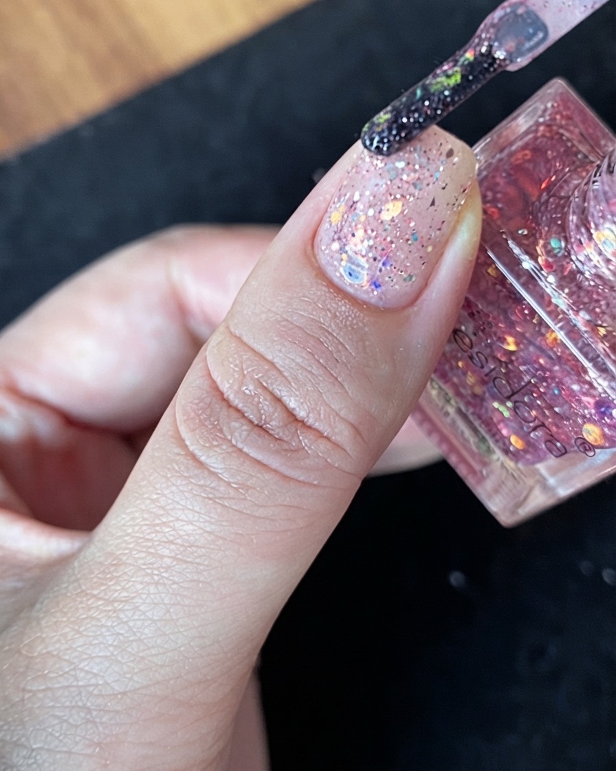 Eine großzügige Ansammlung mehrfarbiger Glitzerflocken direkt in der Mitte eines Nude-Nafels.