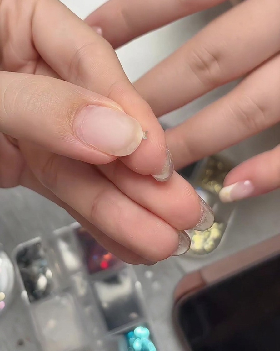 Finger, die ein winziges Stern-Glitterstück sanft drücken, um es in eine geschwungene dreidimensionale Form zu biegen.