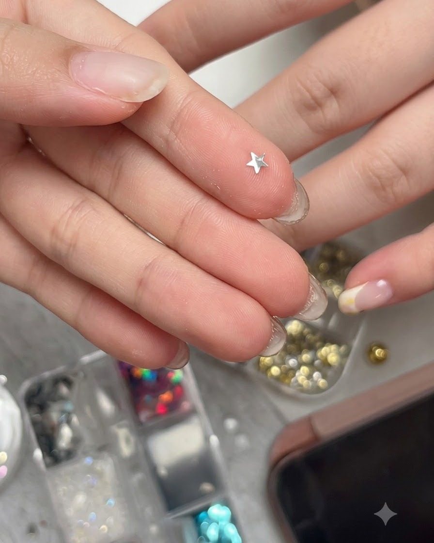 Ein geschwungenes, metallisch silbernes Stern-Glitterteil liegt auf einer Fingerspitze und ist bereit zum Aufnehmen.
