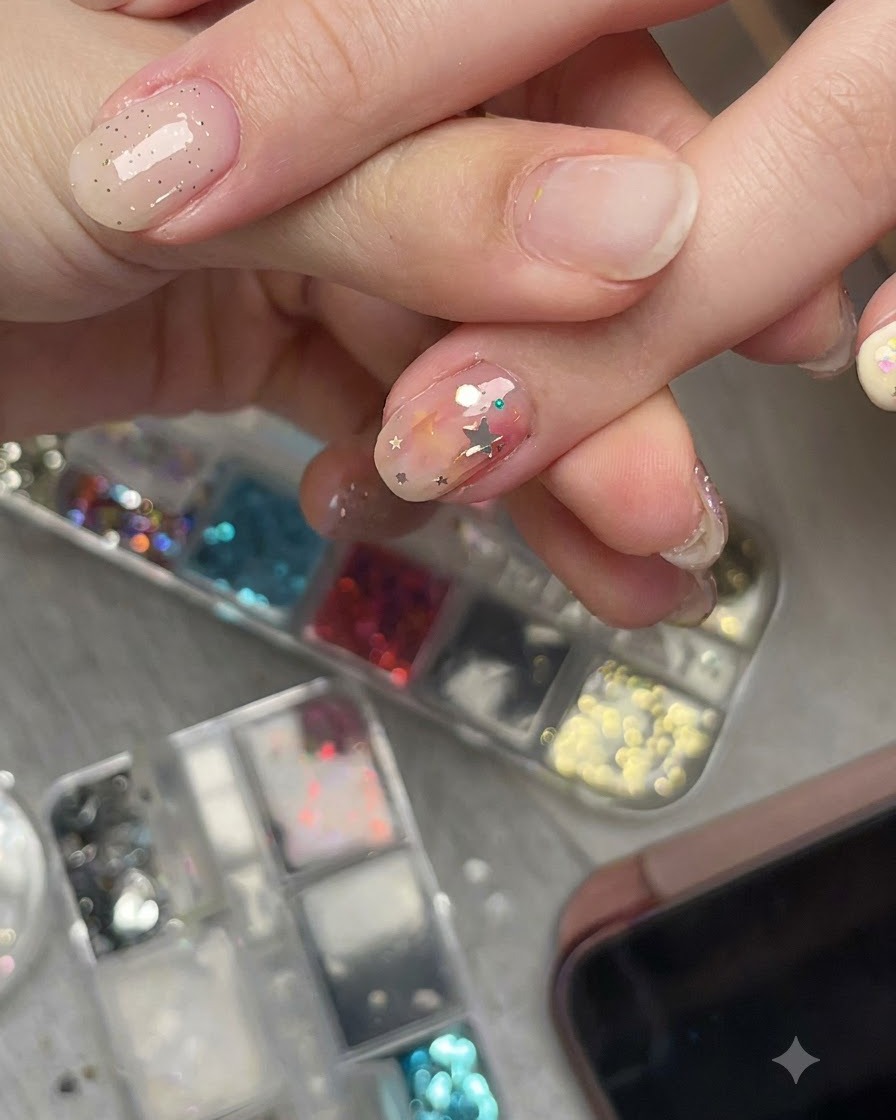 Nahaufnahme einer Hand, die ein vorgebogenes Stern-Glitterstück auf einem Nagel aus einem Seitenwinkel betrachtet, um den bündigen Sitz zu zeigen.