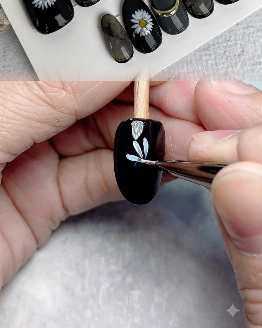 Ein feiner Detailpinsel fügt weitere weiße Blütenblätter hinzu, um die erste Blütenschicht auf einem schwarzen Nagel zu vervollständigen.
