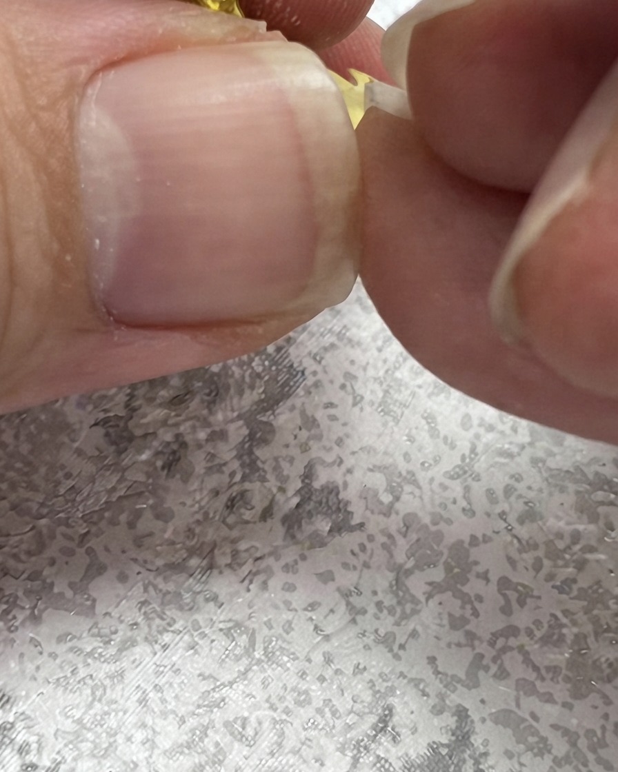 Ein Nagelpinsel zeichnet einen nach oben gerichteten grünen Strich, um neben einem Gänseblümchen eine Blattform zu erzeugen.
