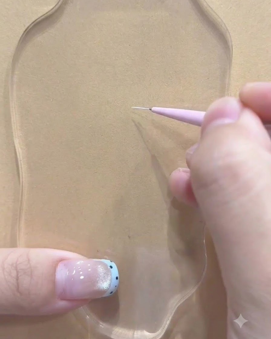 Ein Fine-Liner-Pinsel, gehalten von einer Hand, die den ersten weißen Strich auf einer klaren Palette zieht.