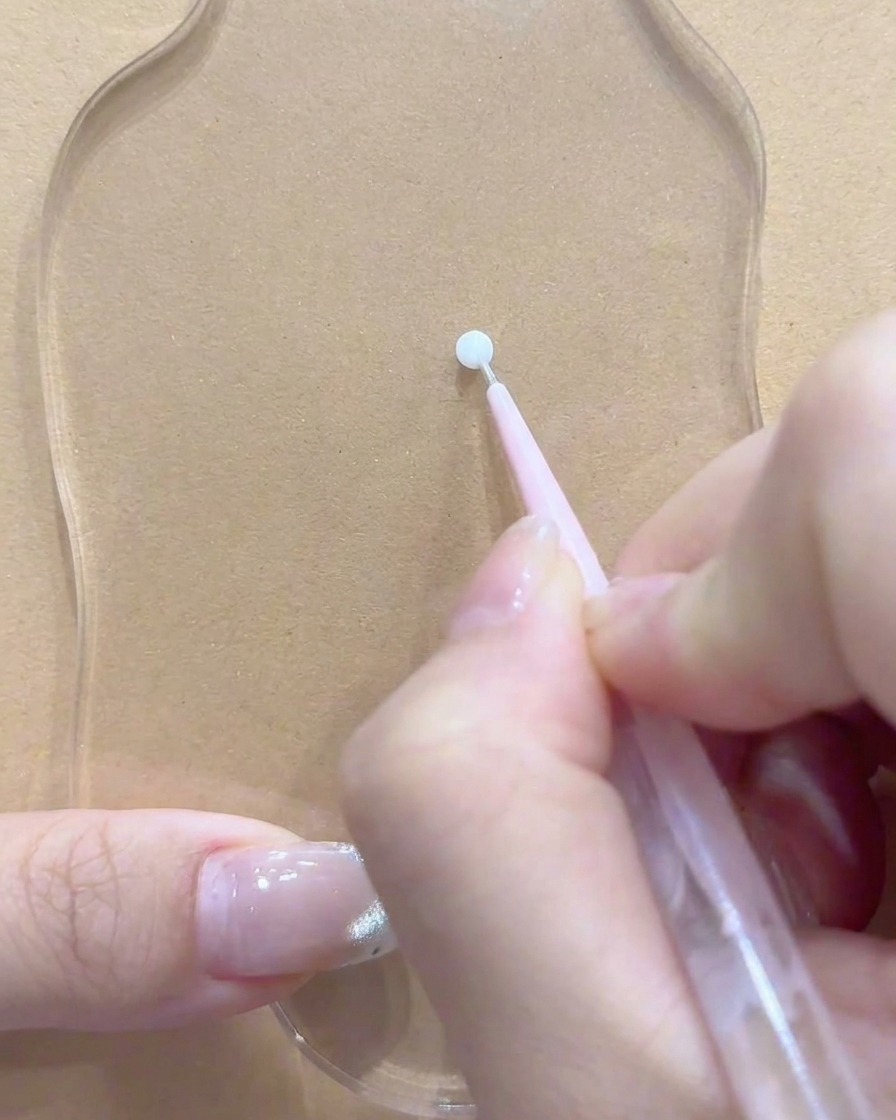 Ein Dotting-Tool oder Pinsel ruht in der Nähe einer sauberen Stelle auf der klaren Acrylpalette.