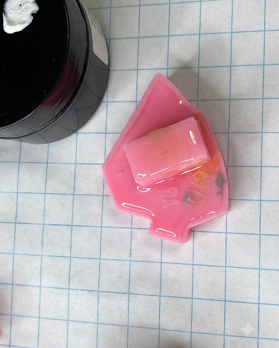 Eine ausgehärtete matte rosa Nagelform ruht auf einer Rasterbastelmatte neben einem Gelglas.