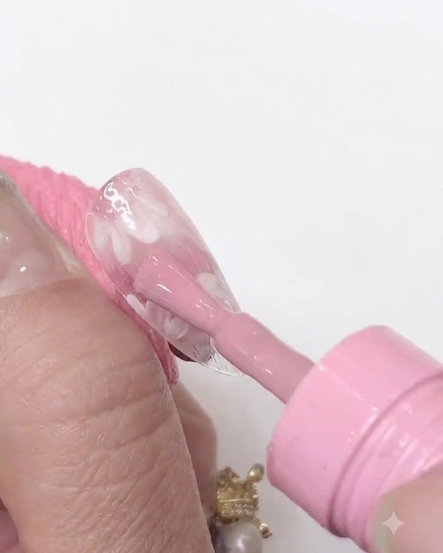 Eine Mini-UV-/LED-Nagellampe, die nah über einen klaren Nagel-Tip gehalten wird, um die aufgetragene Rosagelschicht zu härten.