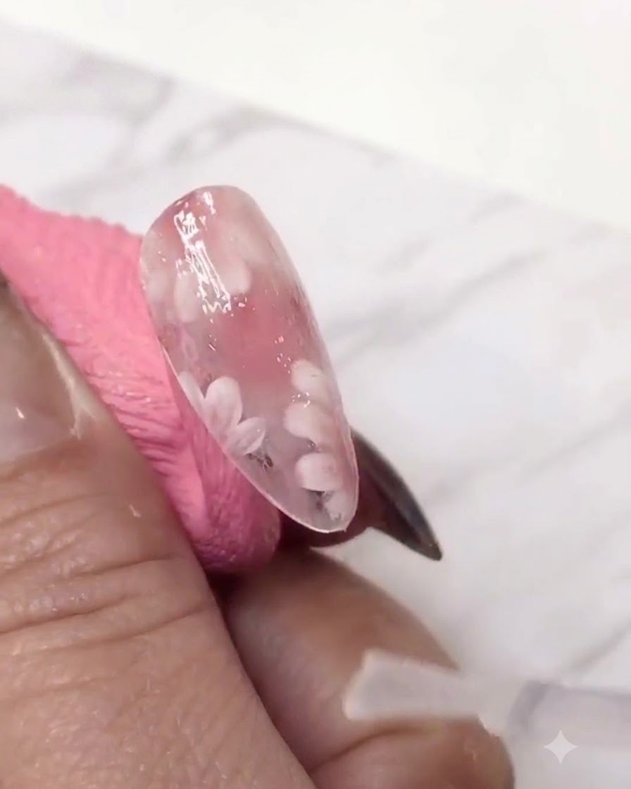 Ein feiner Liner-Pinsel, der eine zweite Schicht weiße Gänseblümchenblätter über die pink getönte Gelschicht für Tiefe hinzufügt.