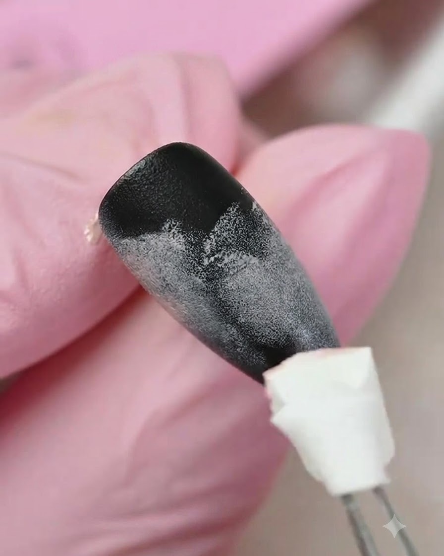 Ein Schwamm-Applikator tupft gelbes Gel auf den unteren Teil eines schwarz-pink verlaufstexturierten Nagels.