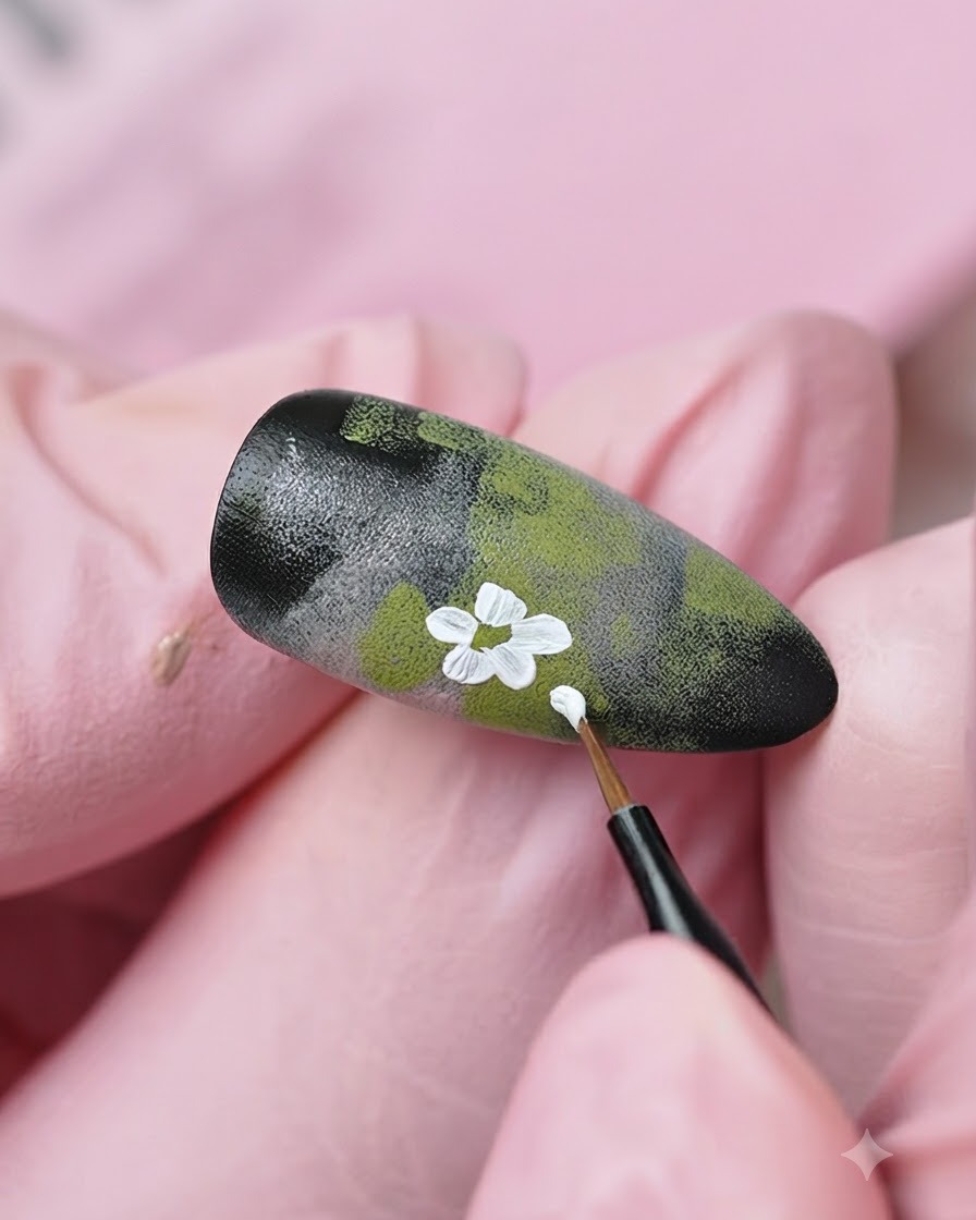 Ein feiner Liner-Pinsel fügt dem texturierten Nageldesign weitere weiße Blumendetails und Knospen hinzu.